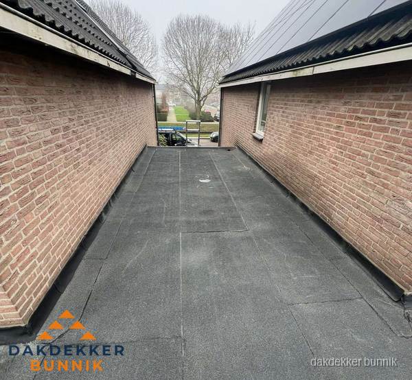 Plat dak met bitumen dakbedekking tussen bakstenen muren in Bunnik Plat dak met bitumen dakbedekking tussen bakstenen muren in Bunnik