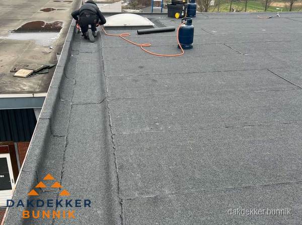 Dakdekker repareert bitumen dakbedekking op groot plat dak in Bunnik Dakdekker repareert bitumen dakbedekking op groot plat dak in Bunnik